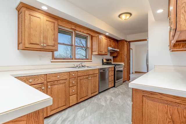 kitchen with a sink, appliances with stainless steel finishes, under cabinet range hood, and light countertops