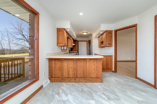 kitchen featuring light countertops, baseboards, visible vents, and brown cabinets