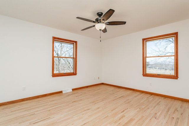 unfurnished room featuring a ceiling fan, baseboards, visible vents, and light wood-type flooring