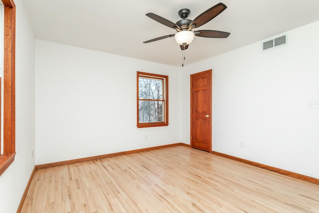 empty room featuring visible vents, light wood-style flooring, a ceiling fan, and baseboards