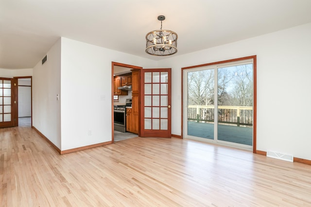 unfurnished room with light wood-type flooring, visible vents, baseboards, and a notable chandelier