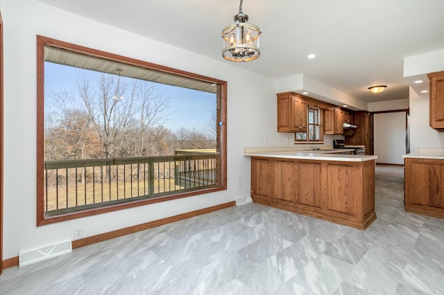 kitchen with light countertops, range, visible vents, and brown cabinets