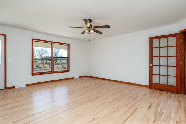 empty room with visible vents, light wood-style flooring, baseboards, and ceiling fan