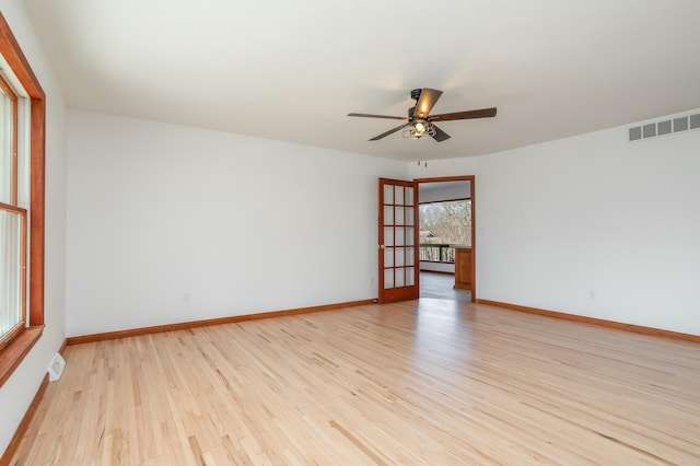 spare room with visible vents, a ceiling fan, light wood-type flooring, and baseboards