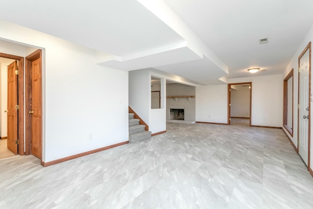 finished basement featuring stairway, baseboards, and a brick fireplace