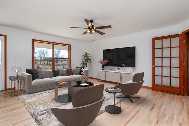 living area featuring ceiling fan, baseboards, and wood finished floors