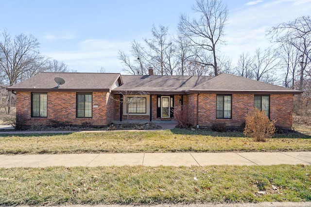 ranch-style home featuring a chimney, a front lawn, and brick siding