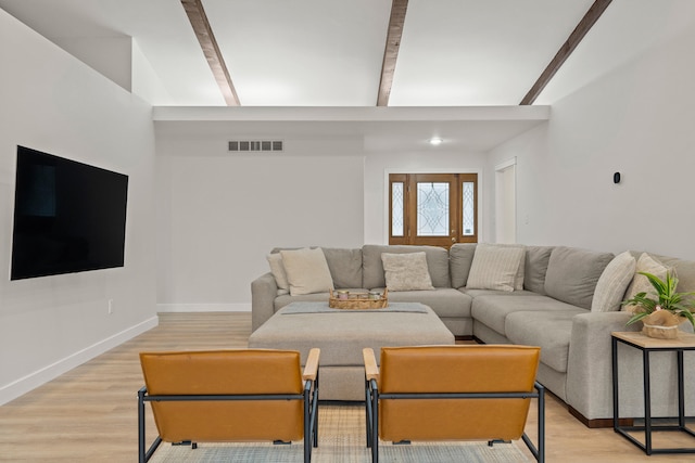 living area with light wood-type flooring, visible vents, baseboards, and beam ceiling