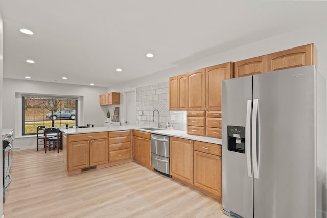 kitchen with light wood-style flooring, stainless steel appliances, a peninsula, a sink, and visible vents