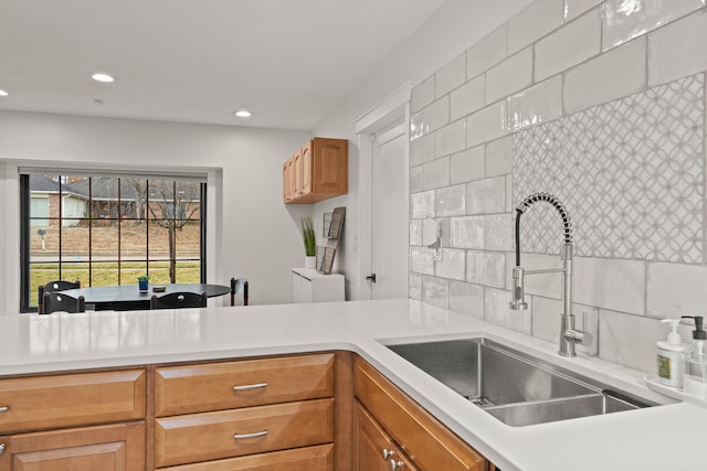 kitchen featuring recessed lighting, light countertops, a sink, and backsplash