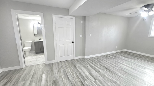 unfurnished bedroom featuring ceiling fan, sink, light hardwood / wood-style floors, and ensuite bath