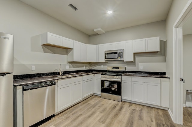 kitchen with appliances with stainless steel finishes, sink, light hardwood / wood-style flooring, and white cabinets