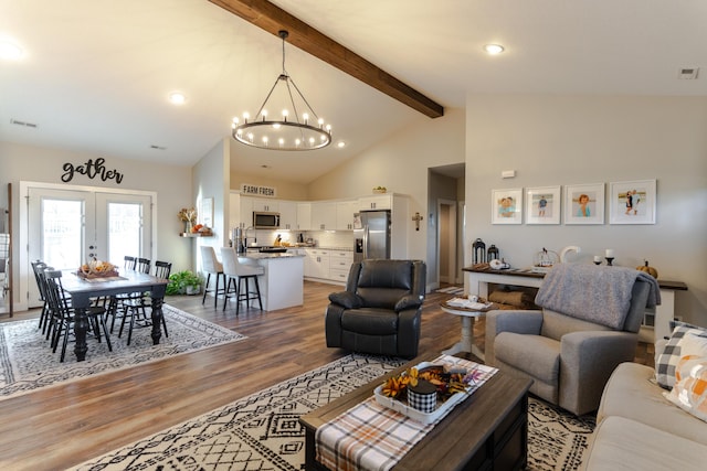 living room featuring hardwood / wood-style flooring, beam ceiling, high vaulted ceiling, a notable chandelier, and french doors