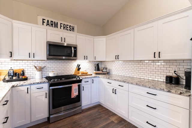 kitchen with vaulted ceiling, white cabinetry, and appliances with stainless steel finishes