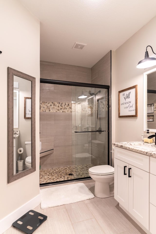 bathroom with vanity, toilet, and a shower with door