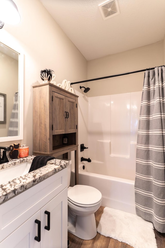 full bathroom with vanity, hardwood / wood-style floors, shower / bath combo, and toilet