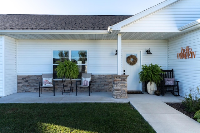 entrance to property with a porch and a yard