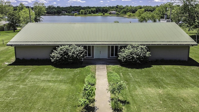 view of front of home with a front lawn, a standing seam roof, and a water view