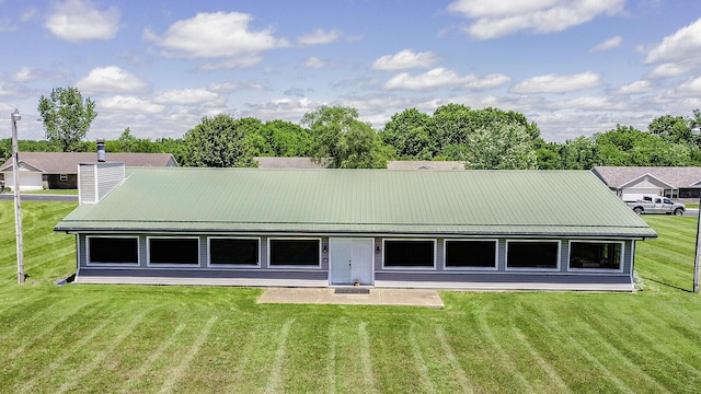 back of house with a chimney, metal roof, and a yard