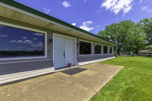 entrance to property featuring a patio and a lawn