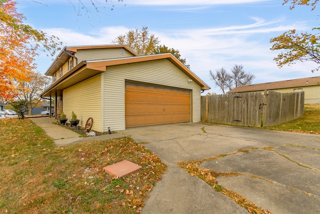 view of side of property featuring a garage, fence, and concrete driveway