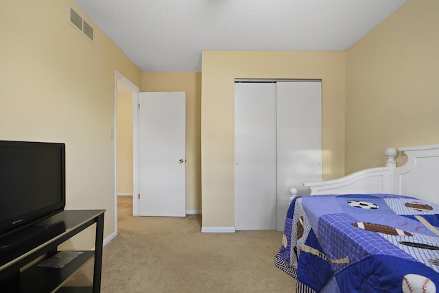 bedroom with a textured ceiling, visible vents, baseboards, a closet, and carpet