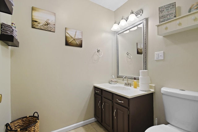 half bathroom featuring toilet, tile patterned floors, baseboards, and vanity