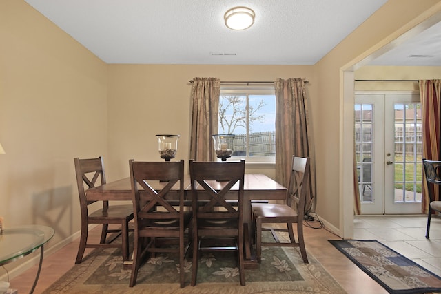 dining area featuring french doors, visible vents, a textured ceiling, wood finished floors, and baseboards