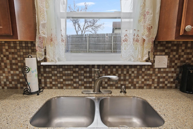 room details featuring tasteful backsplash, light stone counters, and a sink