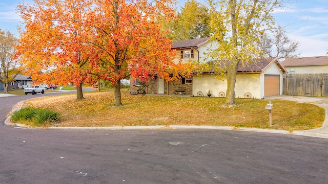 view of front of property featuring a garage, driveway, a front lawn, and fence