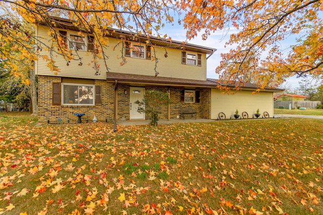 view of front of home featuring a patio area, brick siding, and a front yard