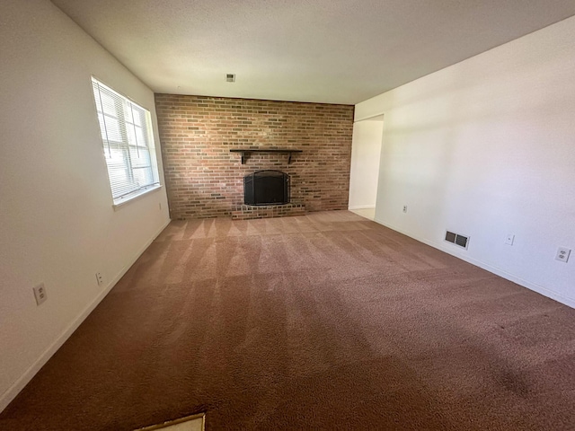 unfurnished living room featuring a brick fireplace and carpet floors