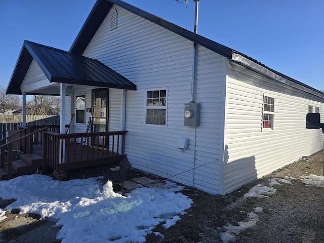 snow covered back of property with covered porch