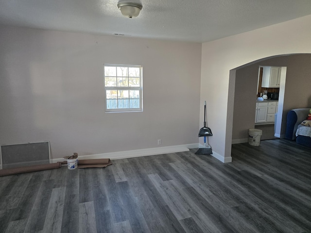 unfurnished room with dark wood-type flooring and a textured ceiling