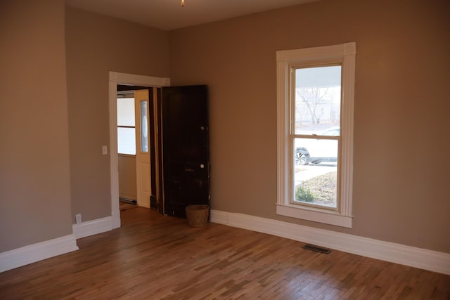 unfurnished room with a healthy amount of sunlight and hardwood / wood-style floors