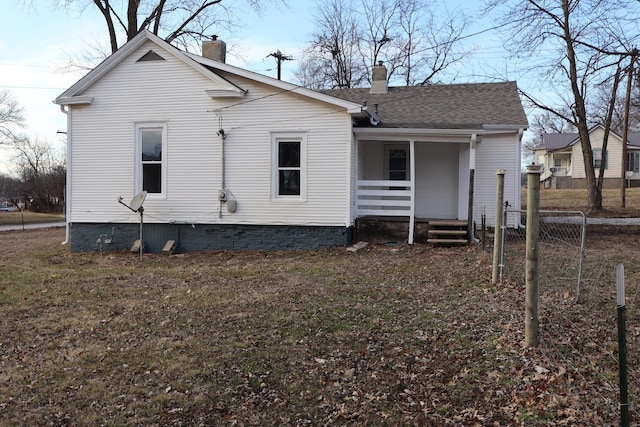 rear view of property with covered porch and a lawn