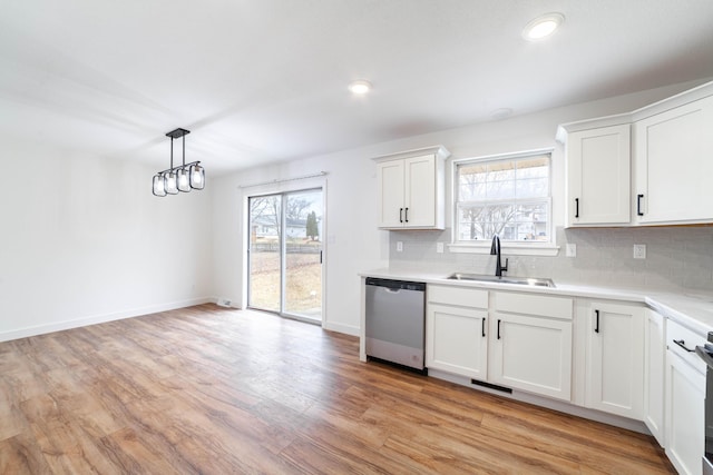 kitchen with sink, tasteful backsplash, dishwasher, pendant lighting, and white cabinets