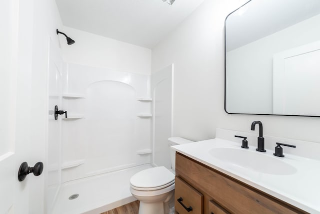 bathroom featuring vanity, hardwood / wood-style flooring, a shower, and toilet