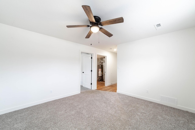 carpeted spare room with ceiling fan and gas water heater