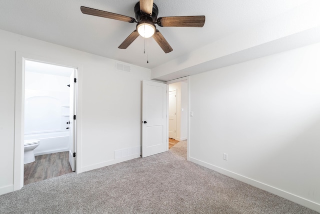 unfurnished bedroom featuring connected bathroom, light colored carpet, and ceiling fan