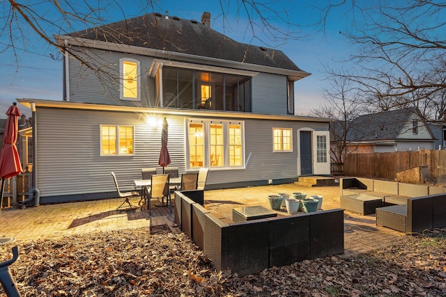 back house at dusk with an outdoor living space and a patio area