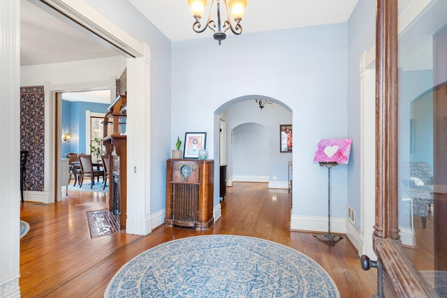 hall with hardwood / wood-style floors and a chandelier