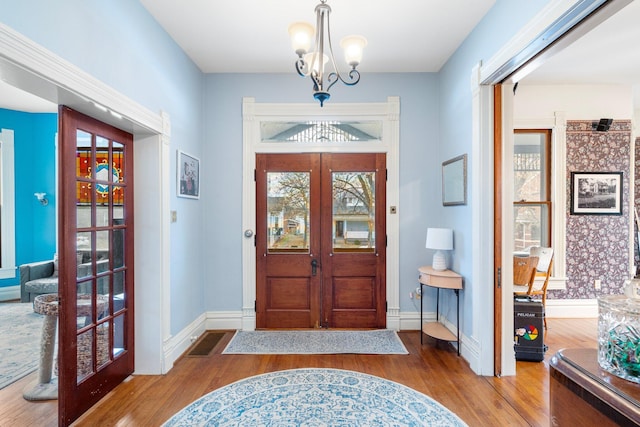 entrance foyer with wood-type flooring, a notable chandelier, and french doors