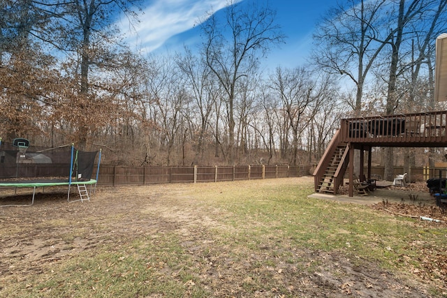 view of yard with a deck, a patio area, and a trampoline