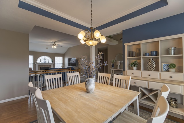 dining room with ceiling fan with notable chandelier, wood-type flooring, ornamental molding, and vaulted ceiling