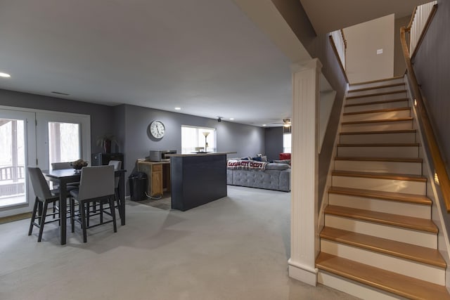 dining space with light carpet, ceiling fan, and a healthy amount of sunlight