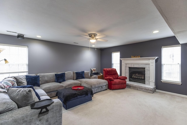 living room with a brick fireplace, light colored carpet, a textured ceiling, and ceiling fan