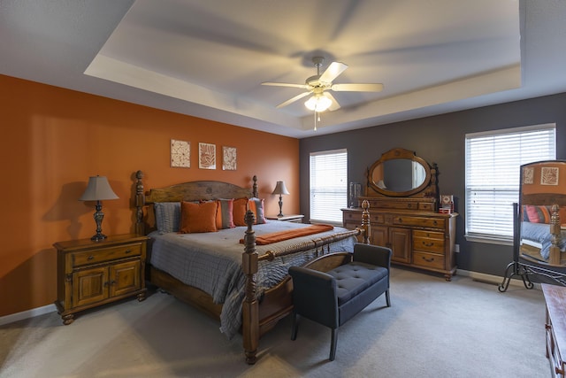 carpeted bedroom featuring a tray ceiling and ceiling fan