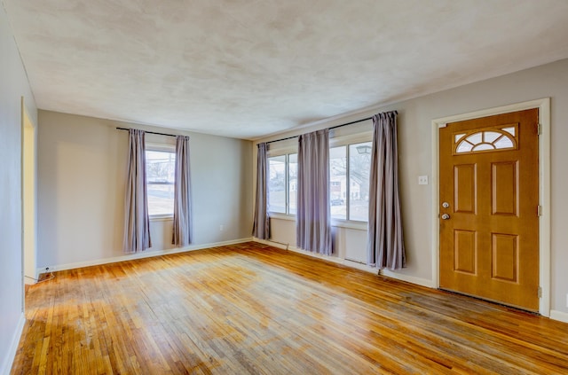 foyer entrance with plenty of natural light, a textured ceiling, and light wood-type flooring