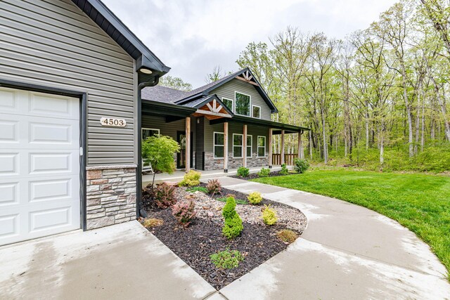 4503 E Mcgee Rd, Columbia, MO 65202 - doorway to property with a lawn, covered porch, an attached garage, and stone siding